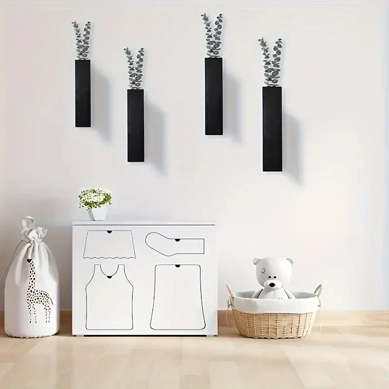 Four sleek, rectangular black wooden wall-mounted vases displaying delicate green stems on a white wall.