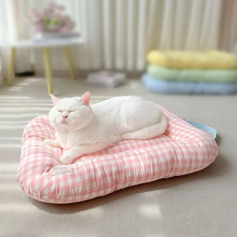 Pink and white checkered rectangular soft pet mat with raised edges, featuring a white cat resting on top.