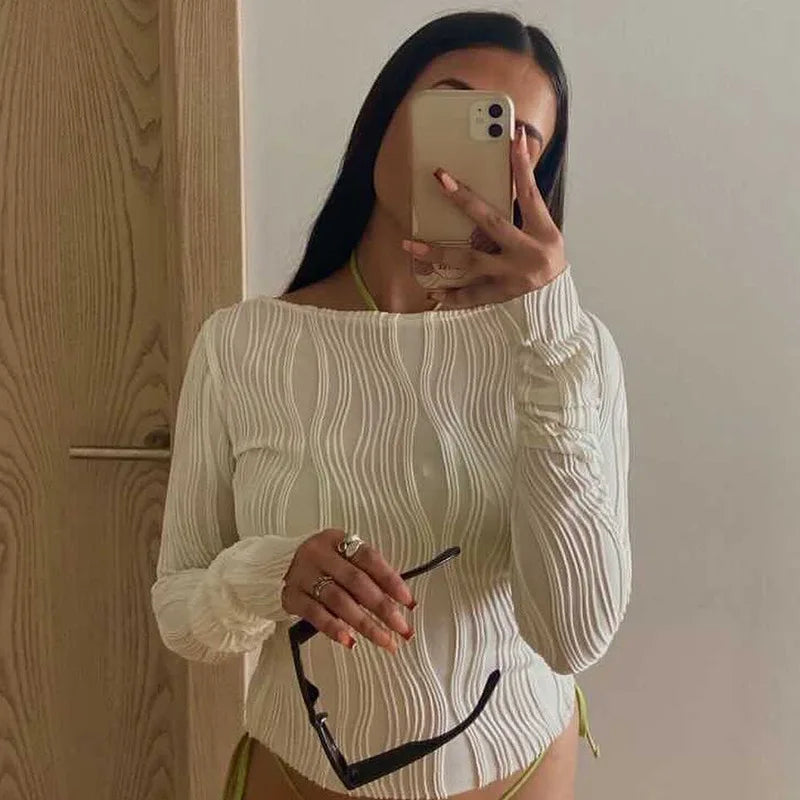 White long-sleeve top with a textured, vertical wavy rib pattern and a round neckline.