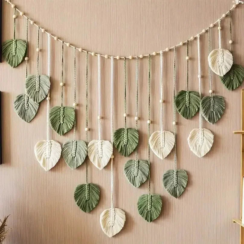 Boho macramé wall hanging featuring sage green and cream leaf-shaped tassels accented with wooden beads.