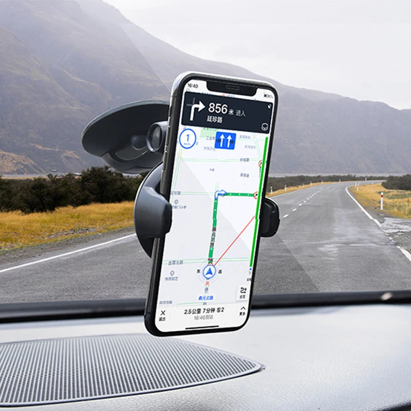 Black universal car phone mount attached to a windscreen, holding a smartphone displaying navigation.