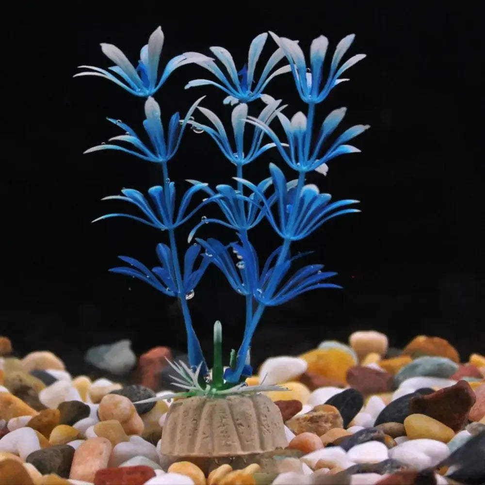 Artificial blue aquarium plant with white-tipped petals on a tan base, set in a bed of colorful aquarium pebbles.
