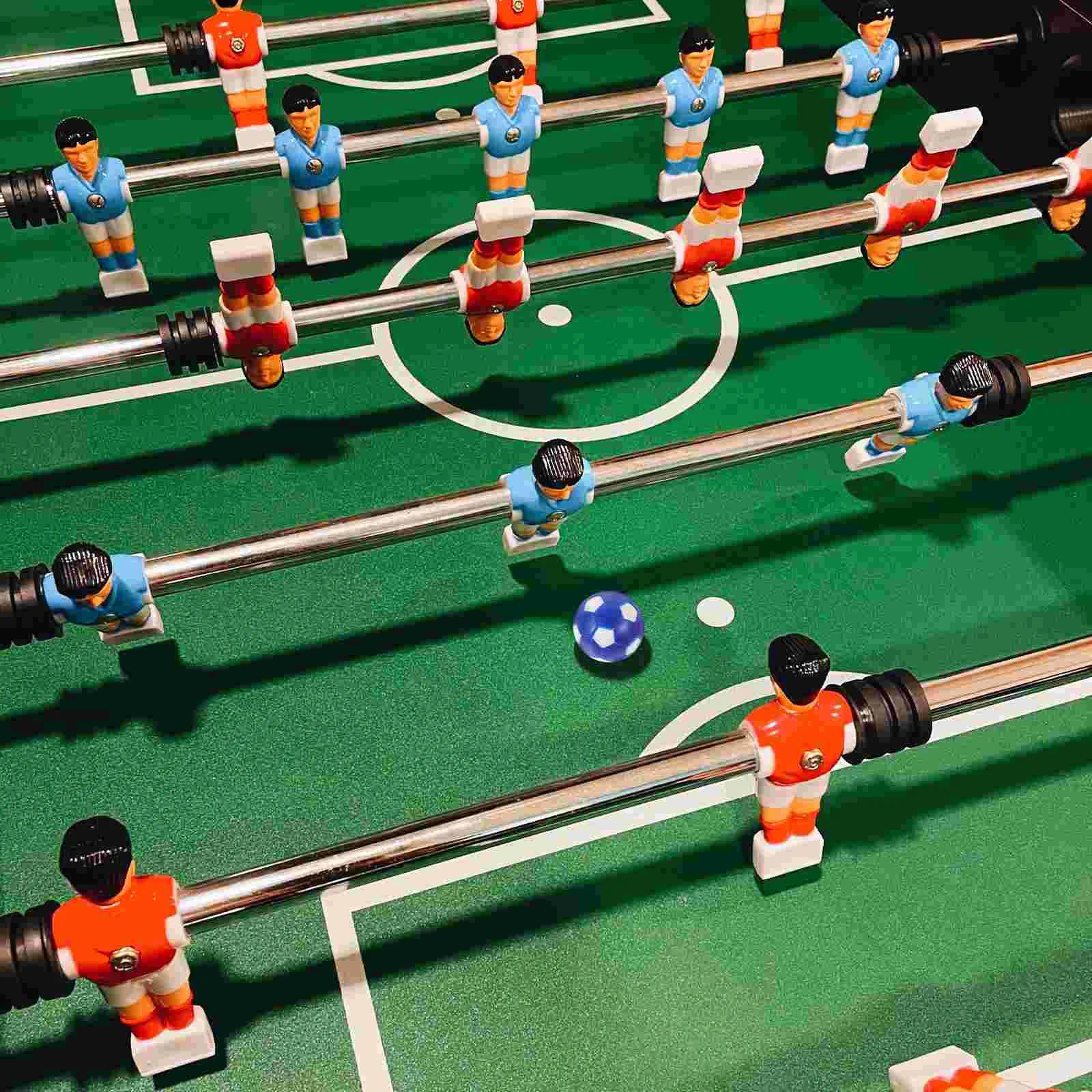 Foosball table with green pitch, metal rods, and blue and orange player figurines with a small blue football.