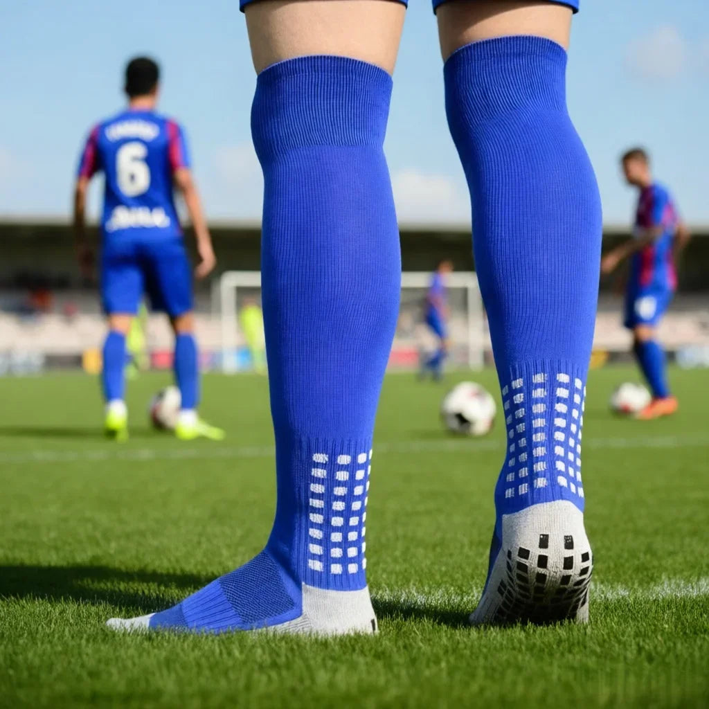 Bright blue knee-high football socks with white patterned grip detail on the calves and soles, worn on a sports pitch.