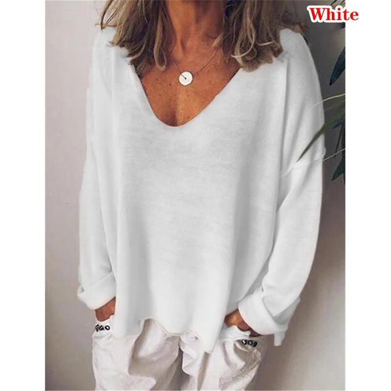 Woman wearing a loose-fit white long-sleeve jumper with a deep V-neckline and dropped shoulders.