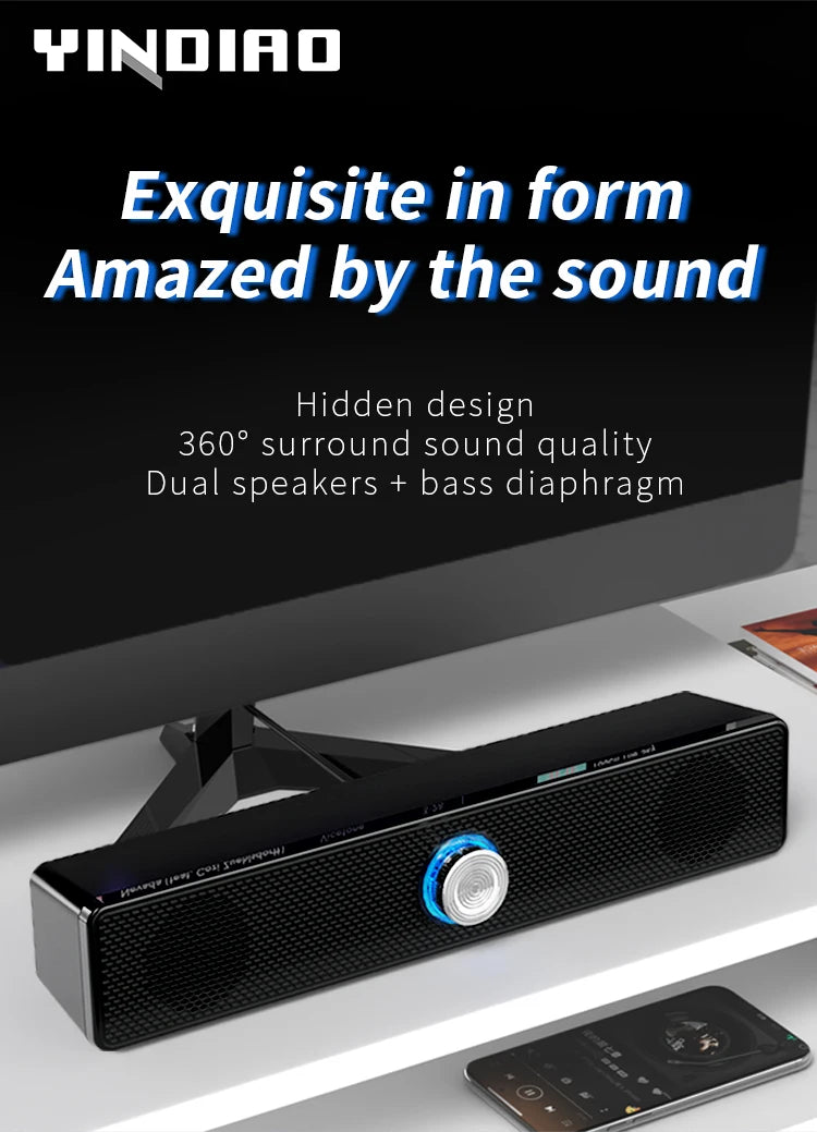 Black USB stereo soundbar with a mesh grille, centre volume dial, and blue LED lighting, sitting under a monitor.