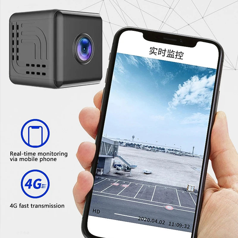 A small, black, cube-shaped wireless indoor security camera shown alongside a smartphone displaying a live HD video feed.