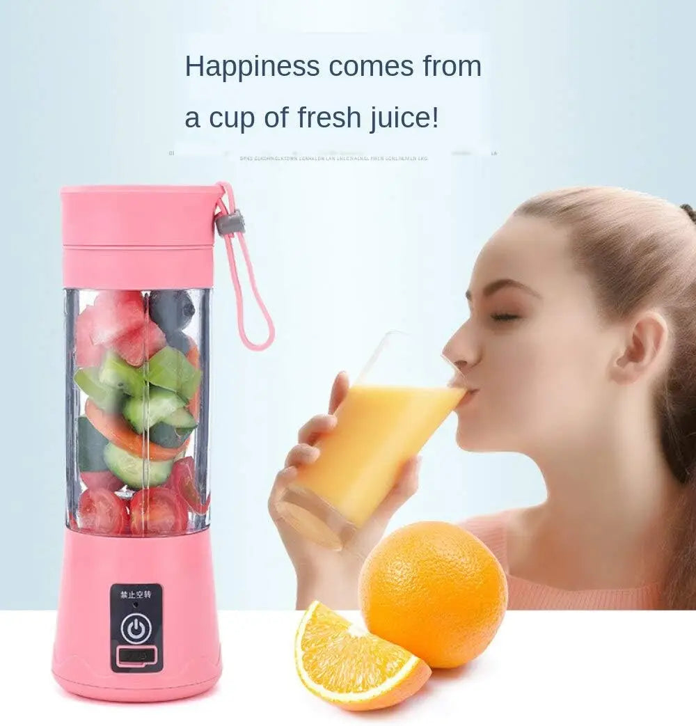 A portable, pink electric blender cup filled with chopped fruit, next to a woman drinking fresh juice.