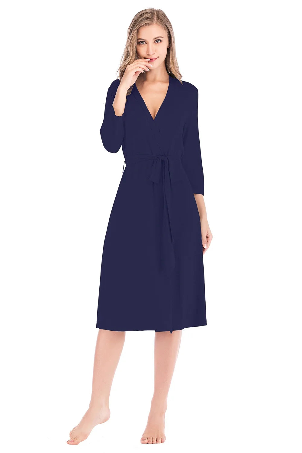 Woman wearing a knee-length, navy blue wrap dress with three-quarter sleeves and a tie waist.