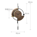 Modern minimalist wall clock with a brown circular face, geometric gold and black accents, and pendulum-style design.