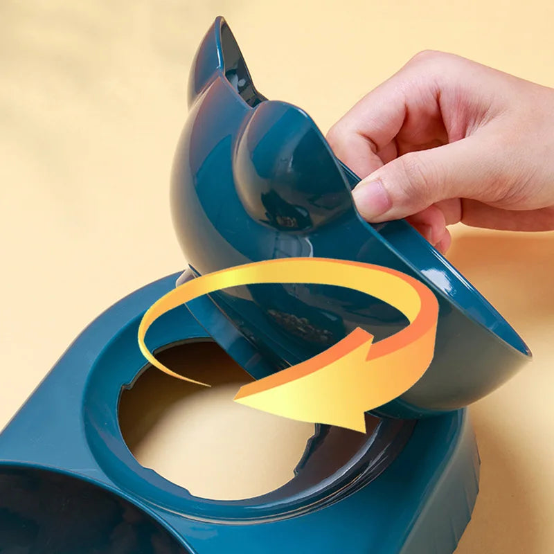 Hand lifting a dark teal, cat-shaped detachable pet bowl from its base, indicated by a circular arrow.