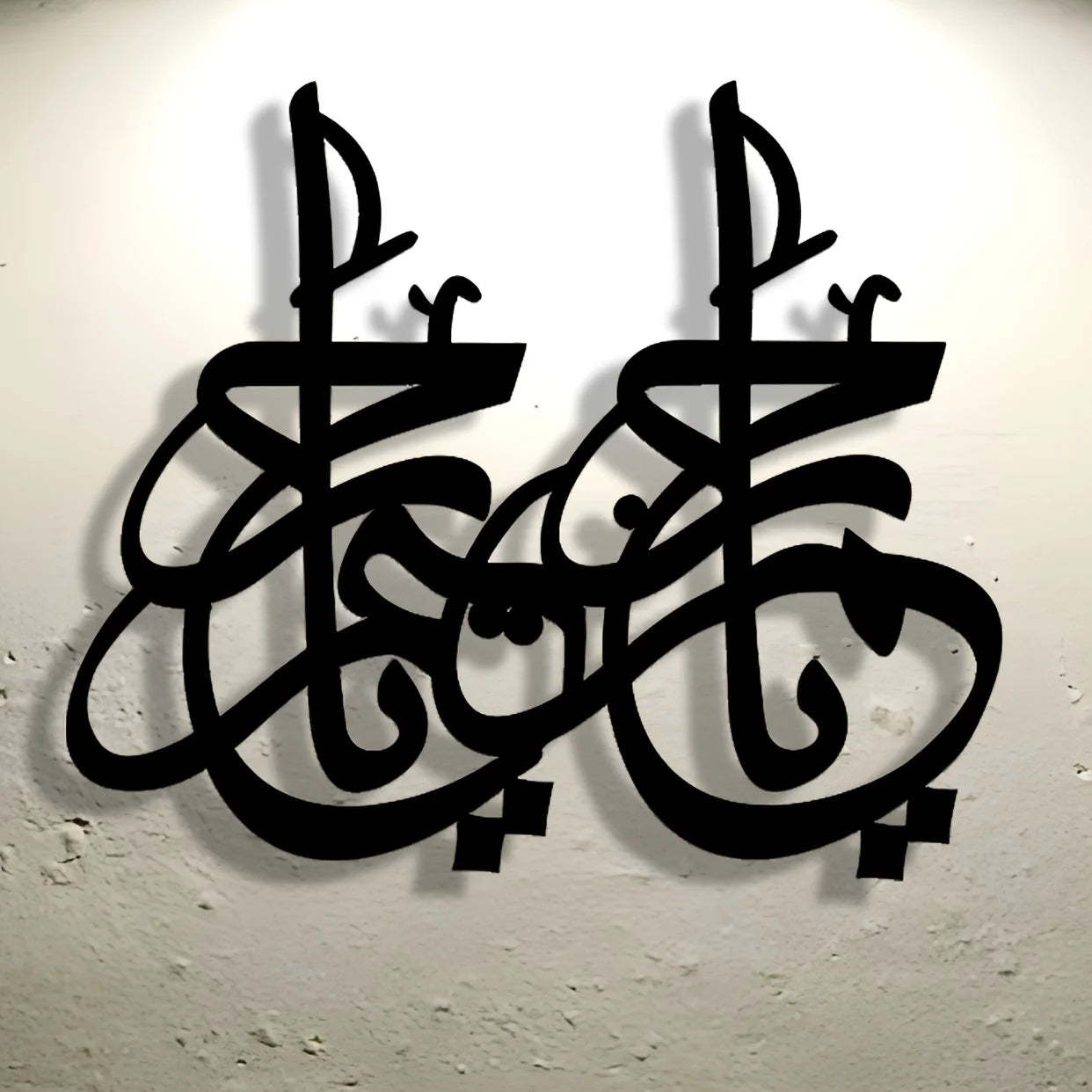 Decorative black metal wall art featuring intricate, modern Arabic calligraphy script with a drop shadow effect.