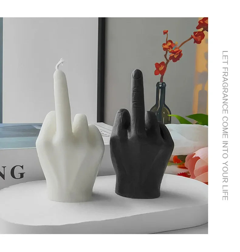 Set of white and black candles shaped like a hand making a middle finger gesture. Modern, sculptural home decor.