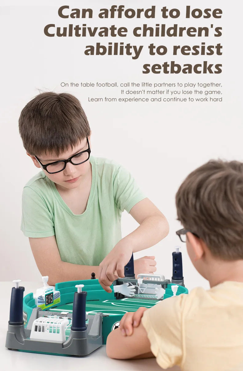 Two children playing a green and grey tabletop football game with built-in score counters and goal posts.
