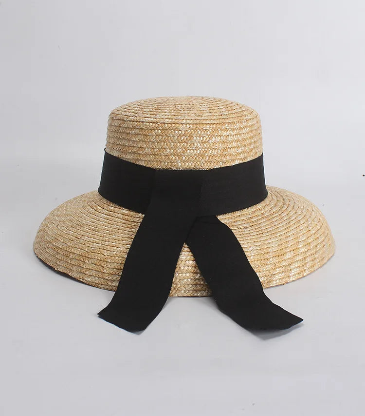 Elegant natural straw sun hat with a wide brim and a black ribbon tied in a bow.