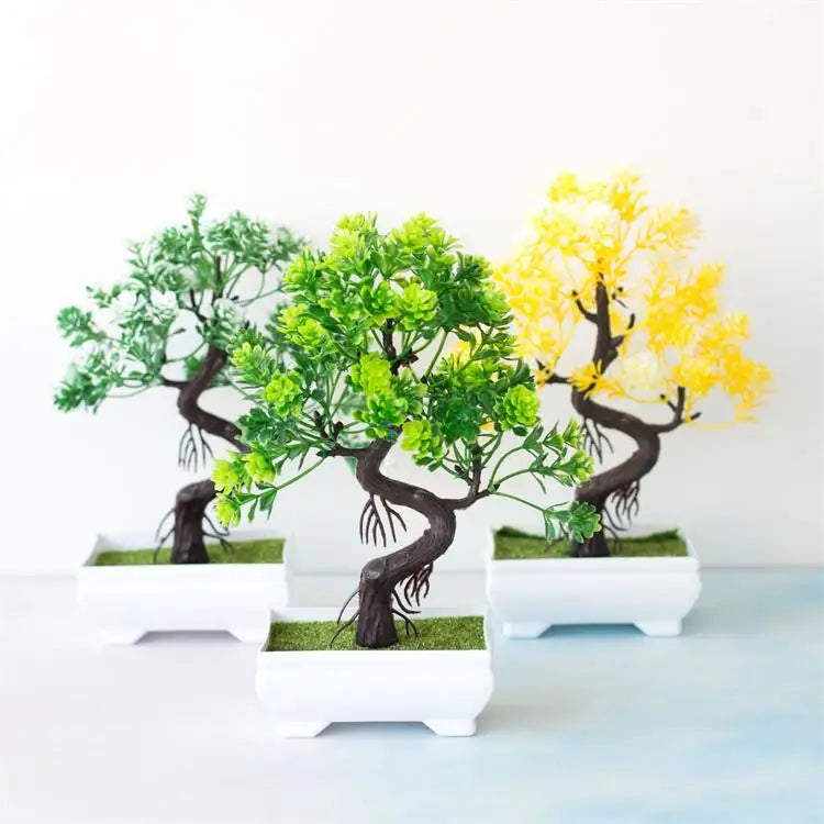 Three artificial bonsai trees with dark twisted trunks and green, yellow, or light green leaves in white square pots.