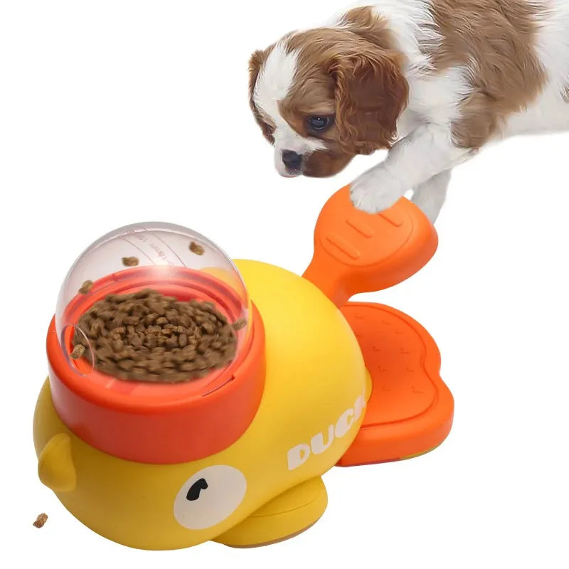 A puppy plays with a yellow and orange duck-shaped interactive treat-dispensing ball toy on a white background.