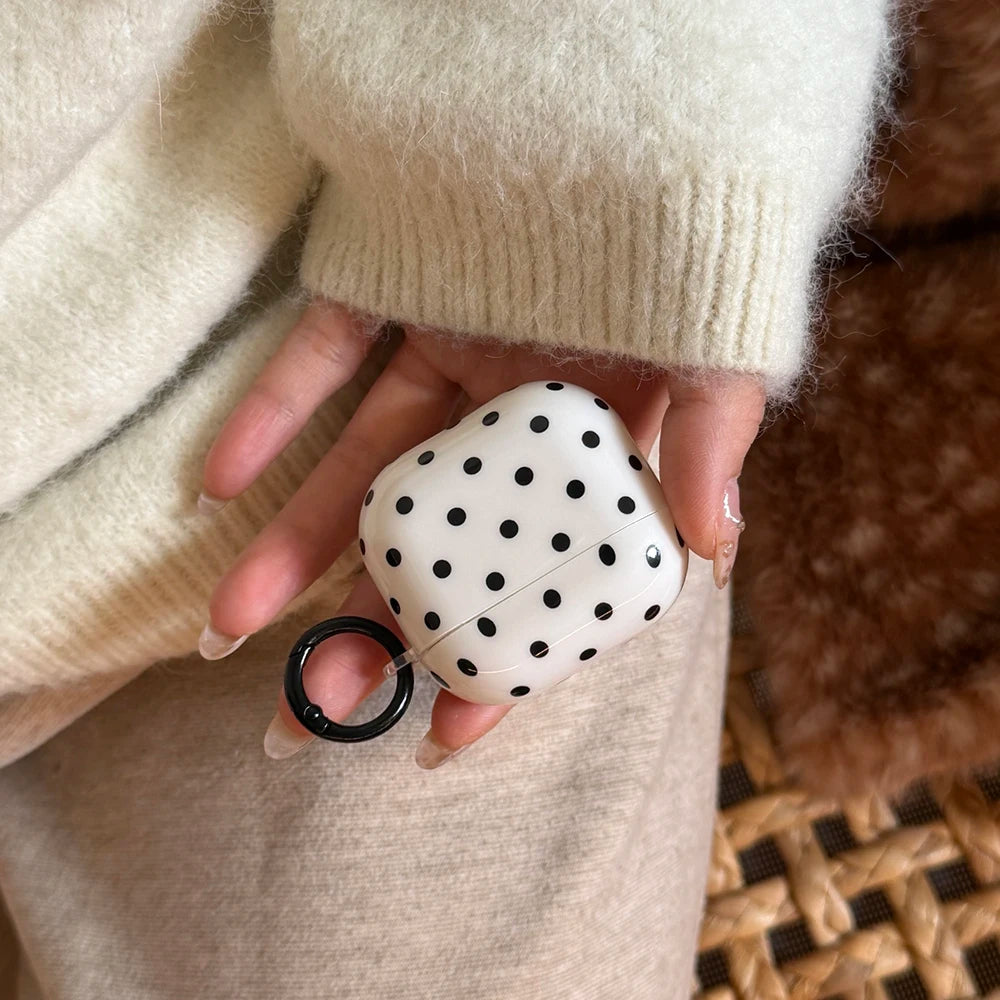 White polka-dot silicone AirPods Pro case with black keyring, held in hand.