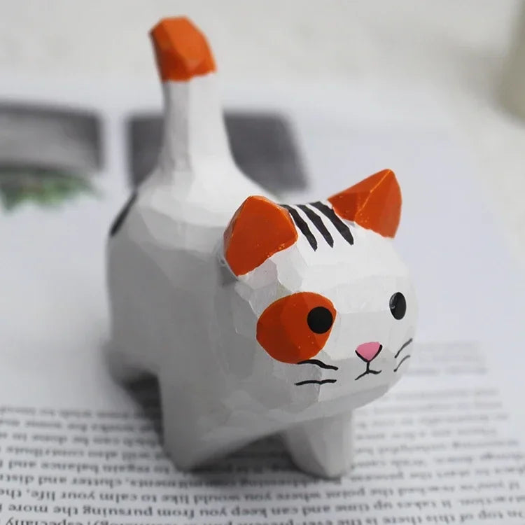 Small, hand-carved wooden cat ornament with a white body, orange ears, and black striped detail.