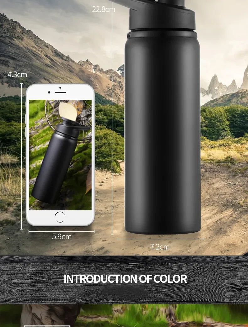 A matte black metal water bottle shown with dimension labels and a smartphone for scale against a mountain backdrop.