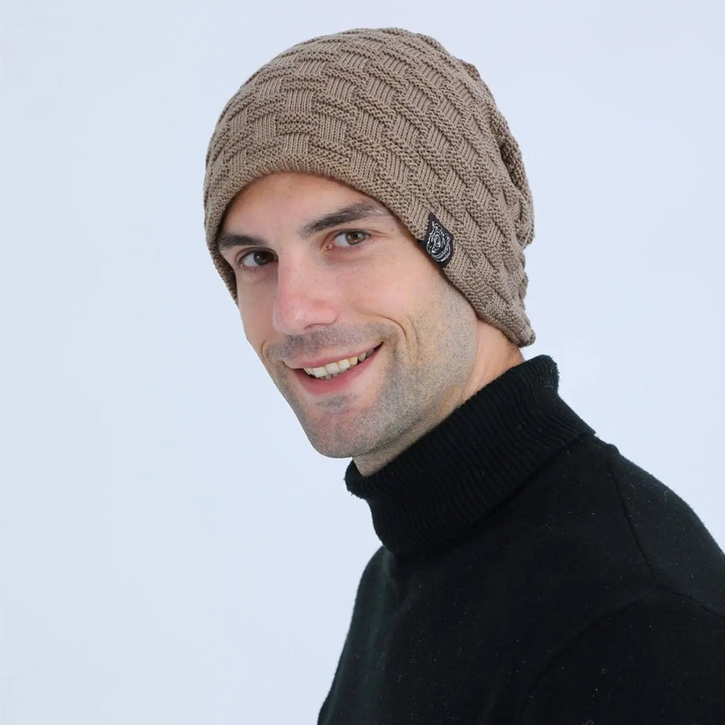 Man wearing a tan-coloured knitted beanie with a textured pattern and a small black side tab.