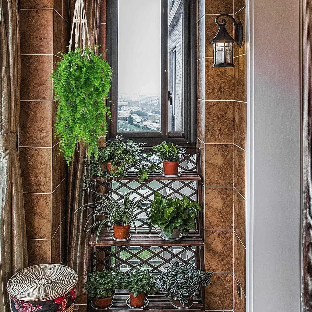 A lush, artificial Boston fern hangs in a macramé planter beside a wooden shelf filled with various small potted plants.