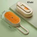 Khaki pet grooming brush with orange silicone bristles, liquid reservoir, and a hanging loop. 12cm x 6.5cm x 4.5cm.
