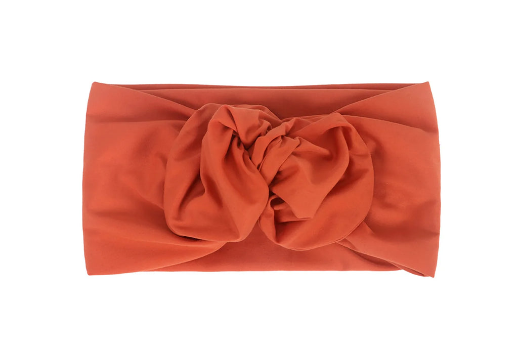 Rust-orange knotted turban headband in a soft, vintage-style fabric.