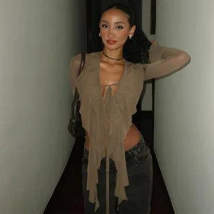 Taupe long-sleeve mesh top with ruffled front detailing and tie-up feature, styled with dark grey jeans.