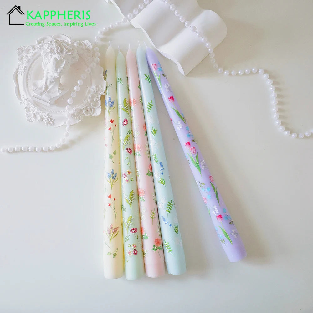 Set of five pastel taper candles featuring delicate floral prints, surrounded by decorative white pearls and accents.