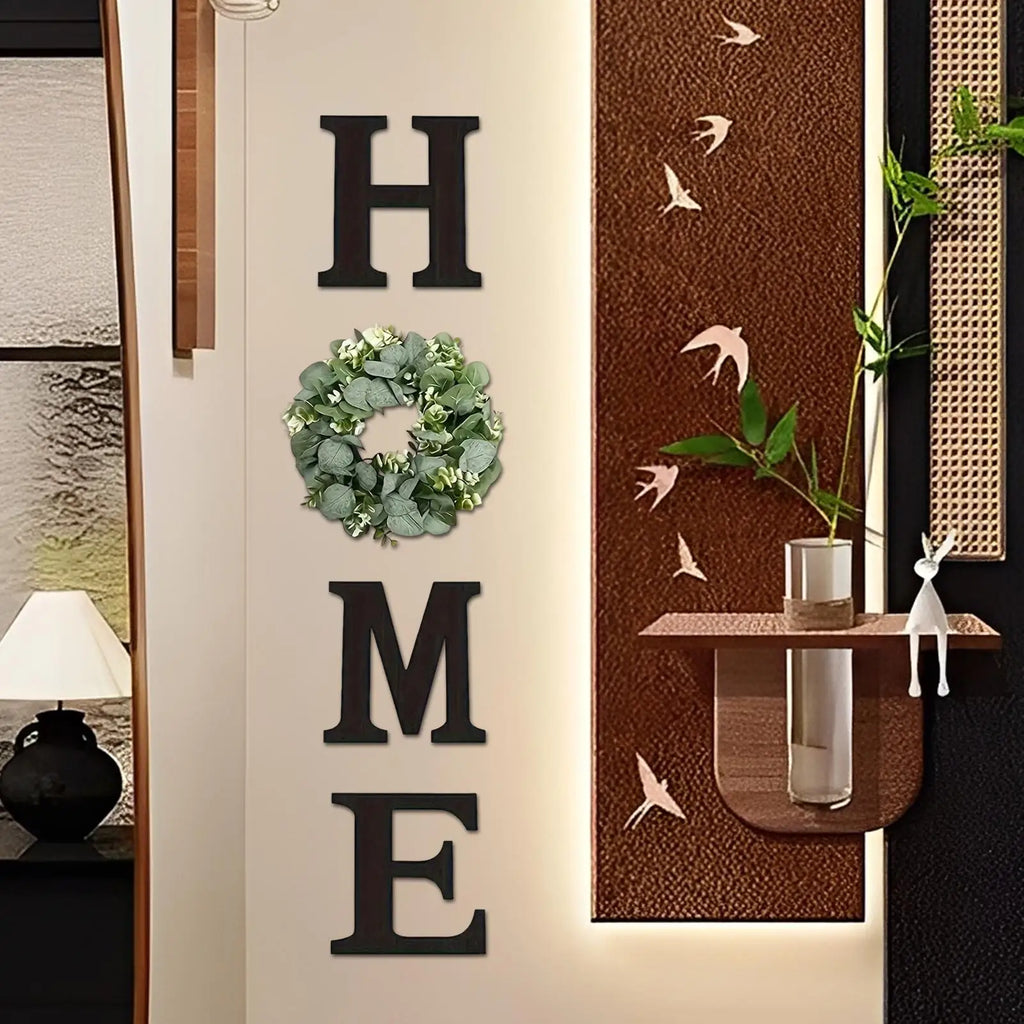 Rustic black wooden "HOME" wall sign featuring a lush artificial eucalyptus wreath replacing the letter O.