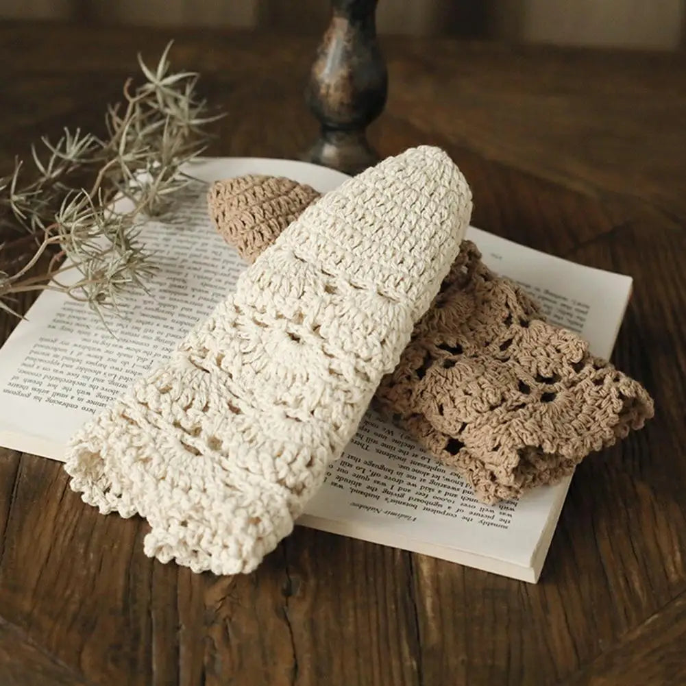 Two delicate, hollow-stitch crochet hats in cream and light brown, resting on an open book.