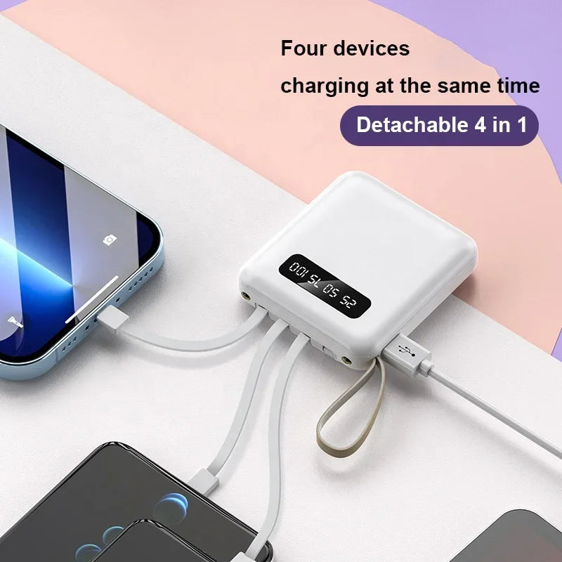 White portable power bank with built-in cables and digital display, charging four devices simultaneously.