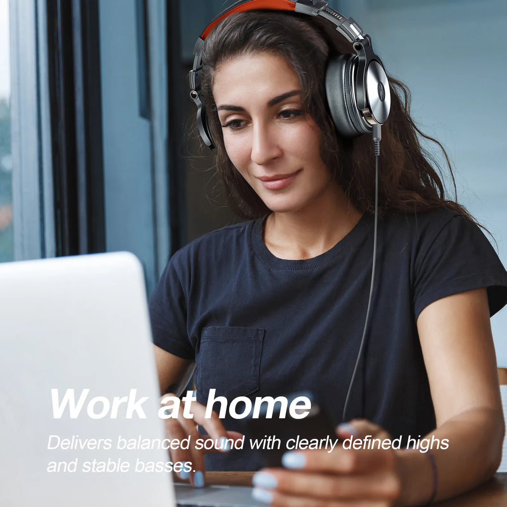 Woman wearing black and silver wired over-ear studio headphones while using a laptop at home.