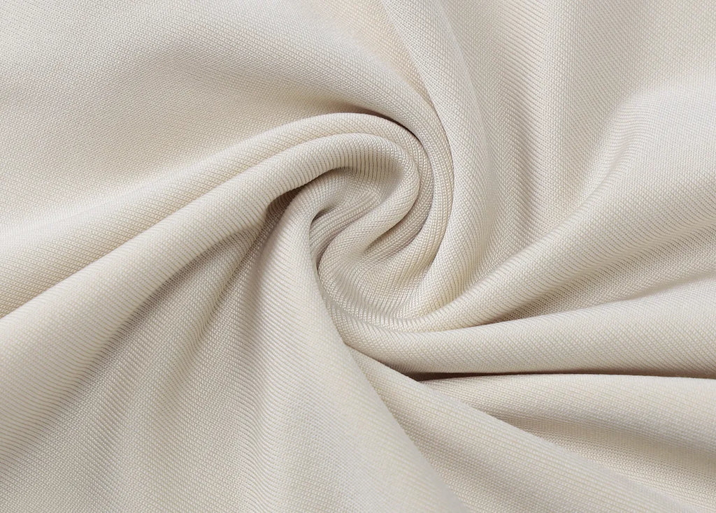 Close-up of smooth, beige fabric with a fine ribbed texture, elegantly draped in a soft spiral swirl.