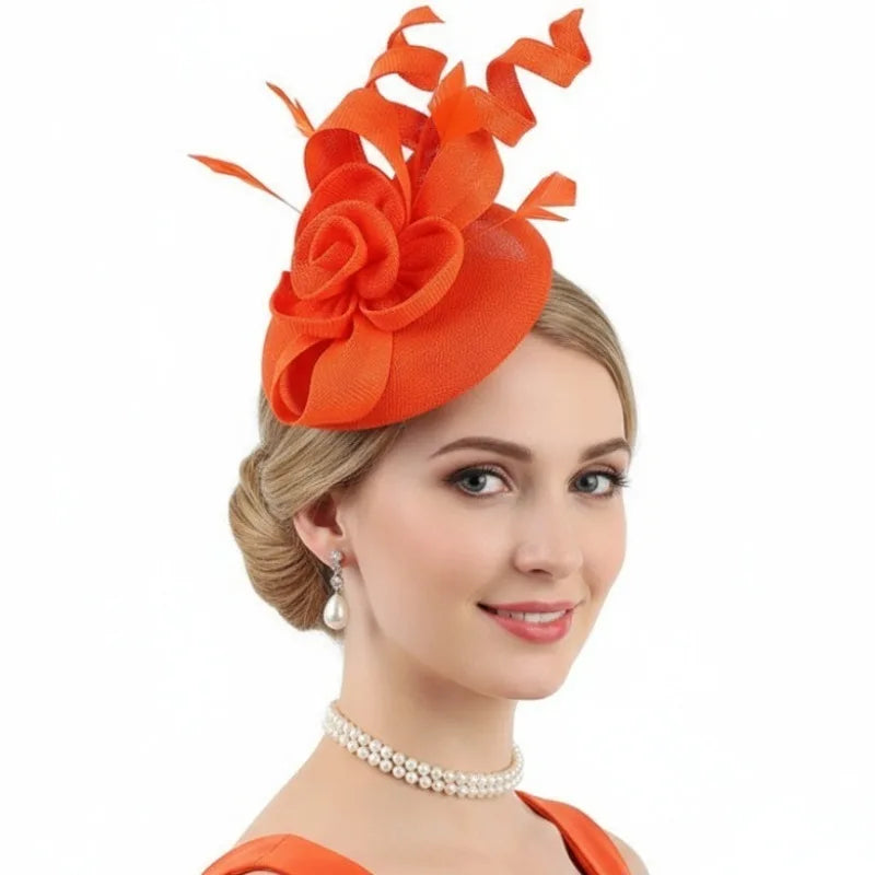 Bright orange fascinator hat with a structured fabric rose, loops, and feathers, worn on the side of the head.