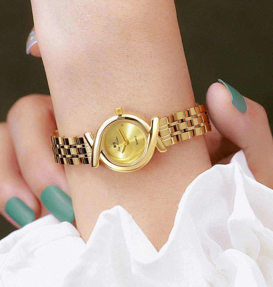 Elegant gold-tone women's quartz wristwatch with a delicate cross-over case design and matching link bracelet.