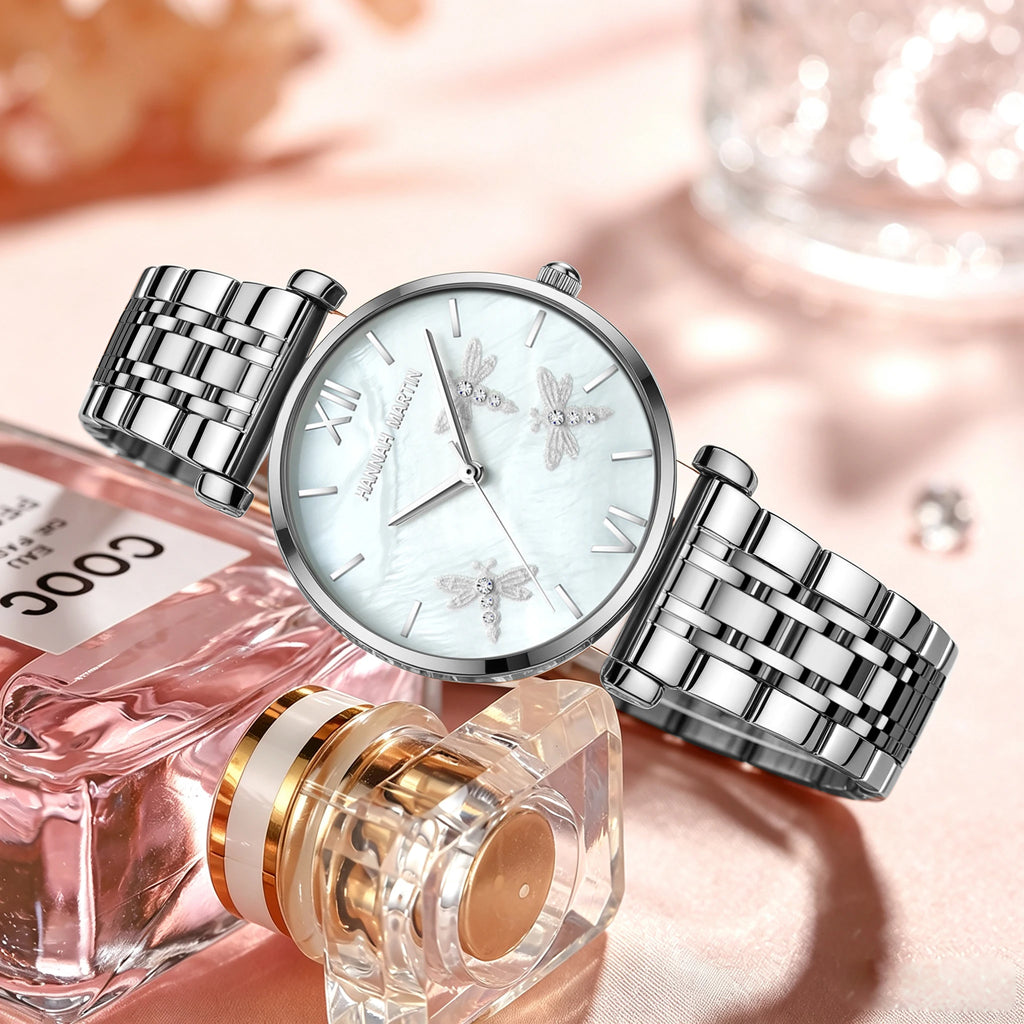 Silver quartz watch with round mother-of-pearl dial, rhinestone dragonfly reliefs, and linked metal band.