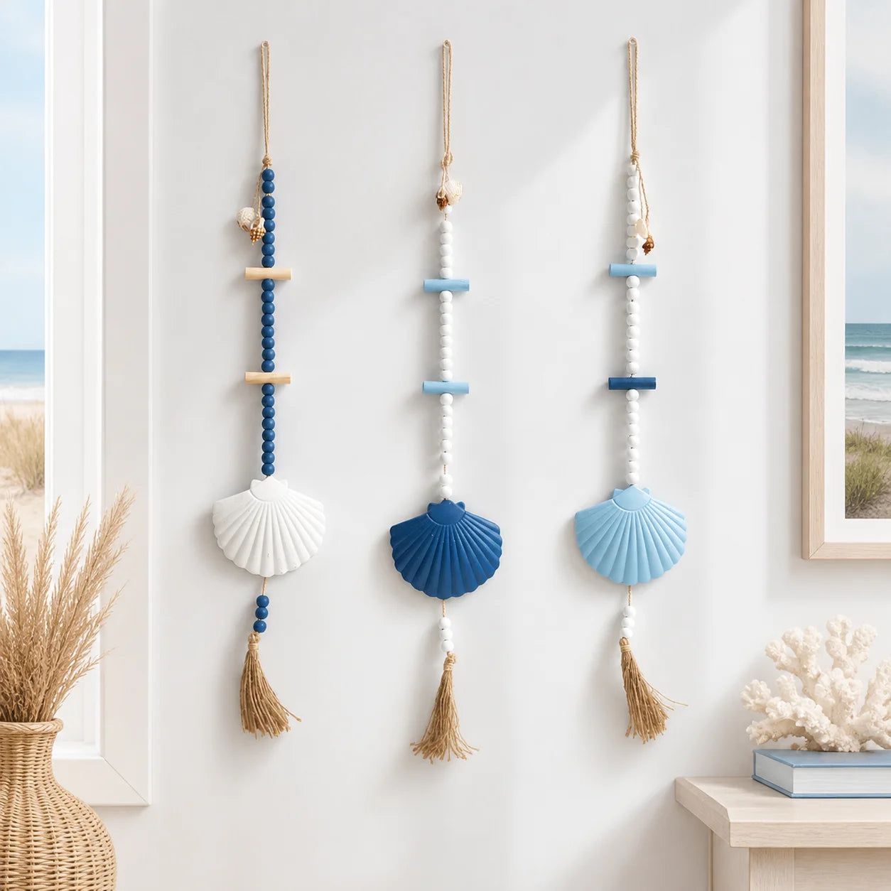 Three boho-style wall hangings featuring blue, white, and wood beads with large seashell accents and jute tassels.