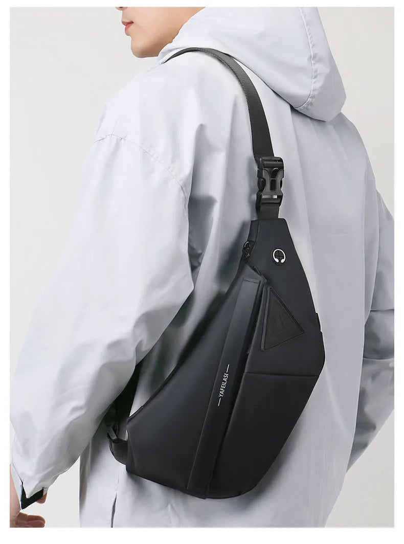 A man wearing a sleek, black anti-theft crossbody sling bag with a secure buckle strap and headphone port.