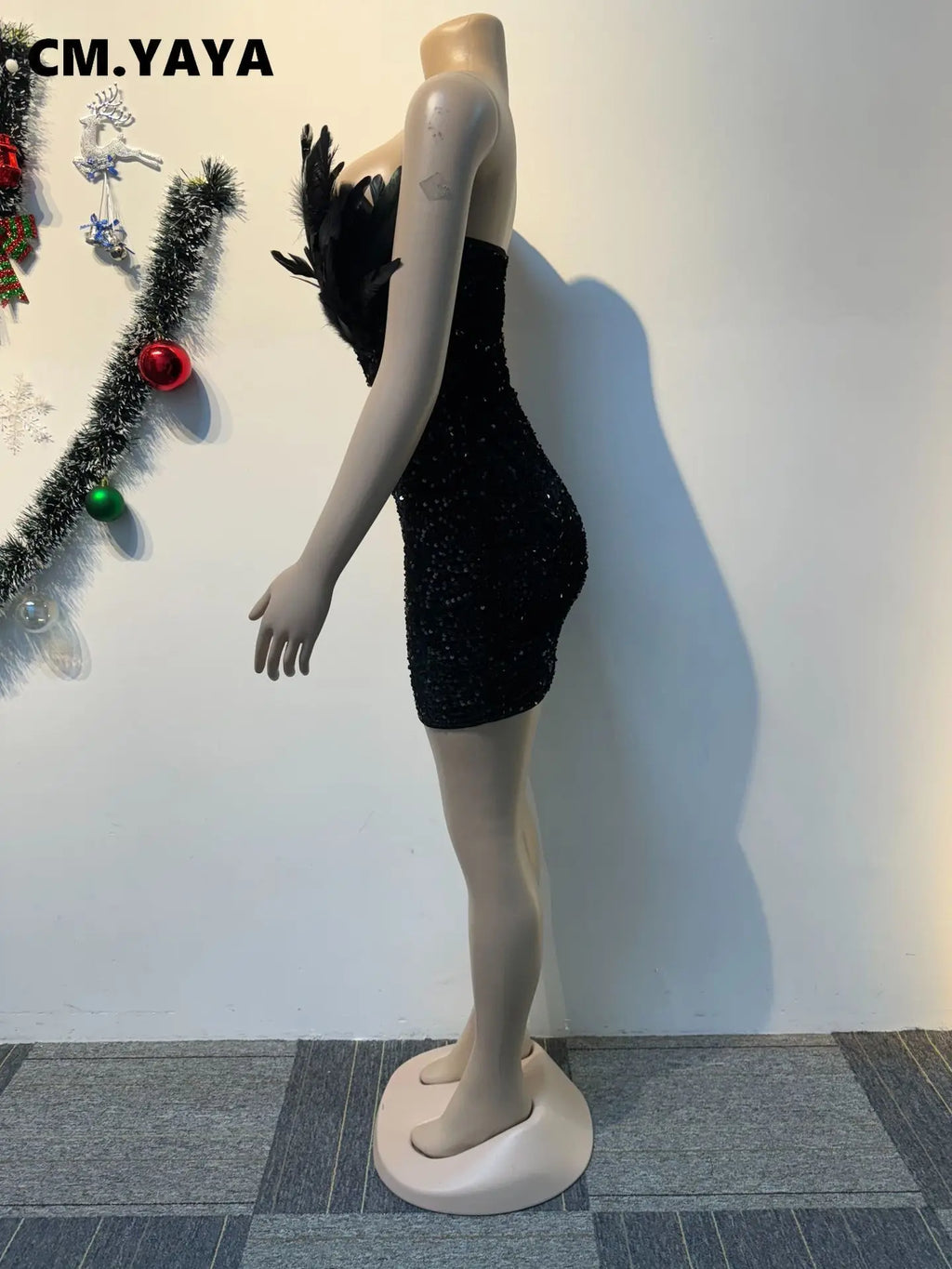 Black sequined strapless bodycon mini dress featuring feather trim on the bust on a mannequin.