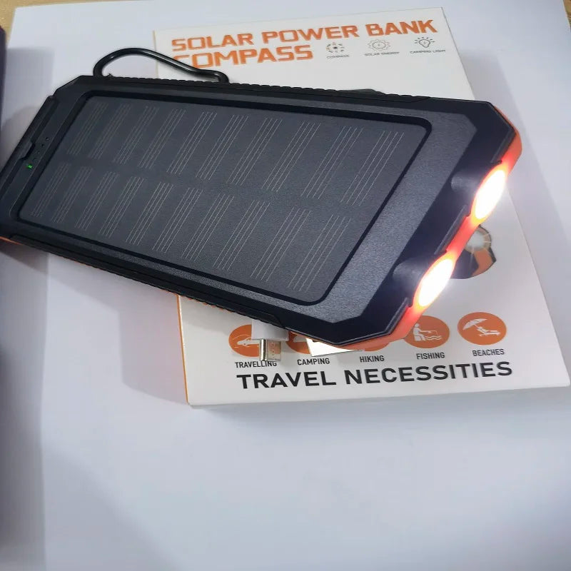 Rugged black and orange solar power bank with built-in LED torch, resting on its white product packaging.