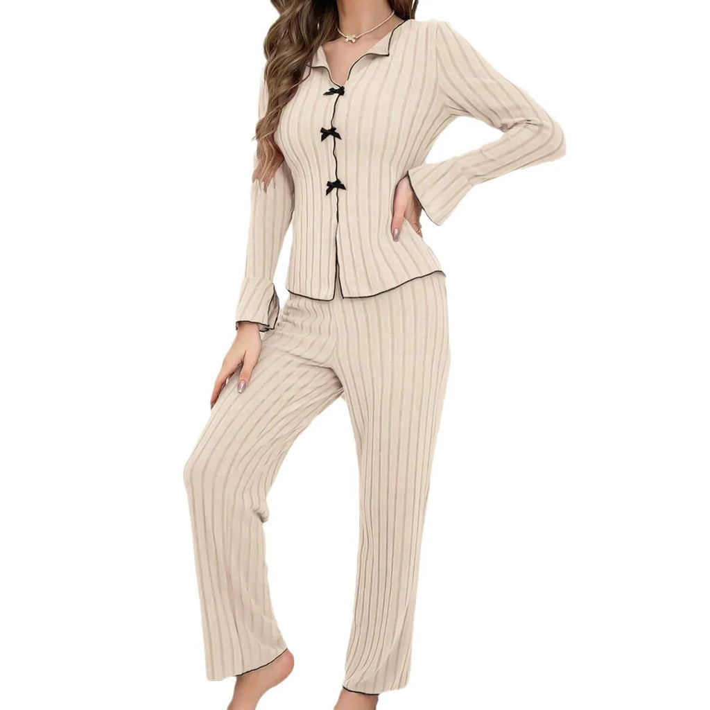 Beige ribbed pyjama set with black contrast trim, long flared sleeves, and decorative bow button detailing.