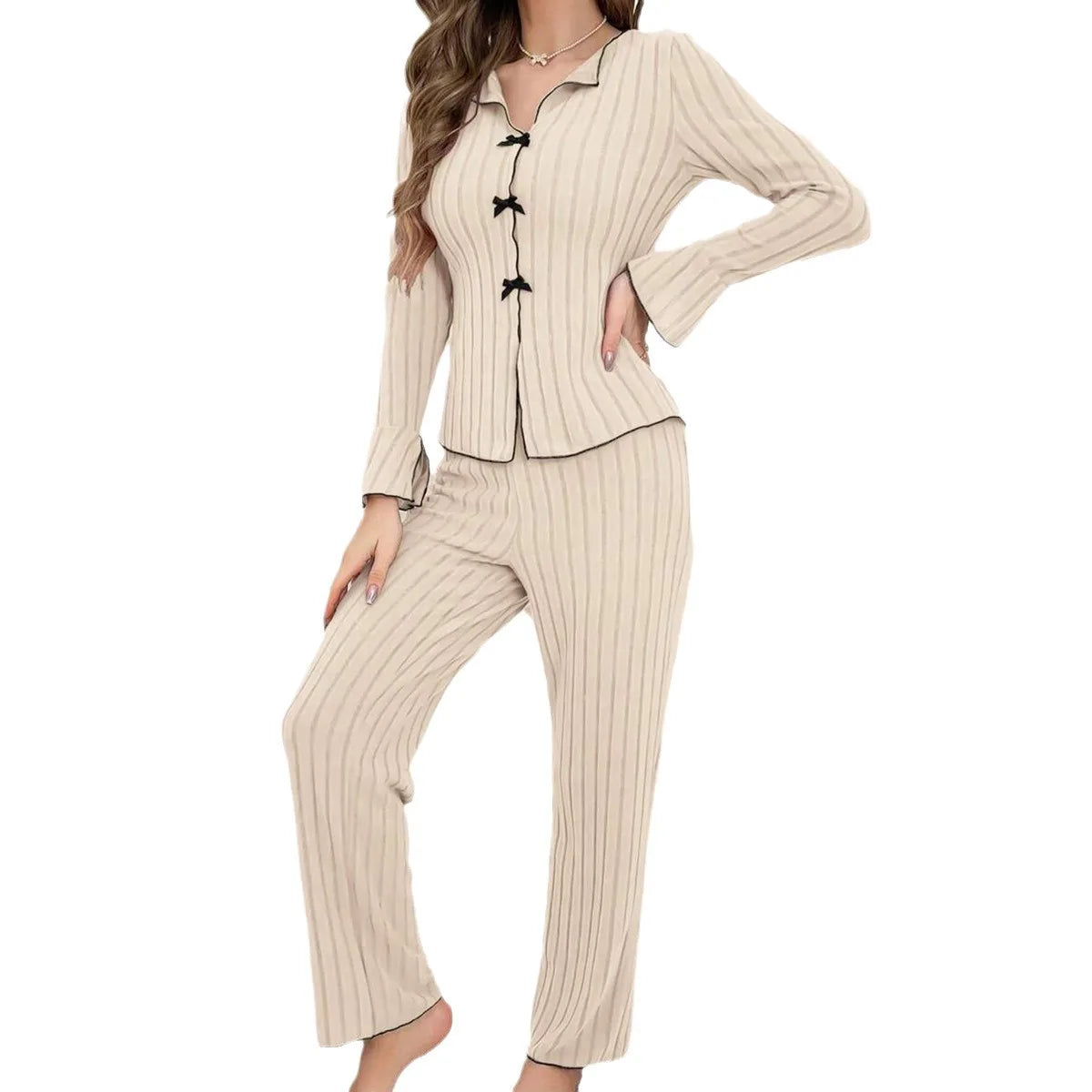 Beige ribbed pyjama set with black contrast trim, long flared sleeves, and decorative bow button detailing.