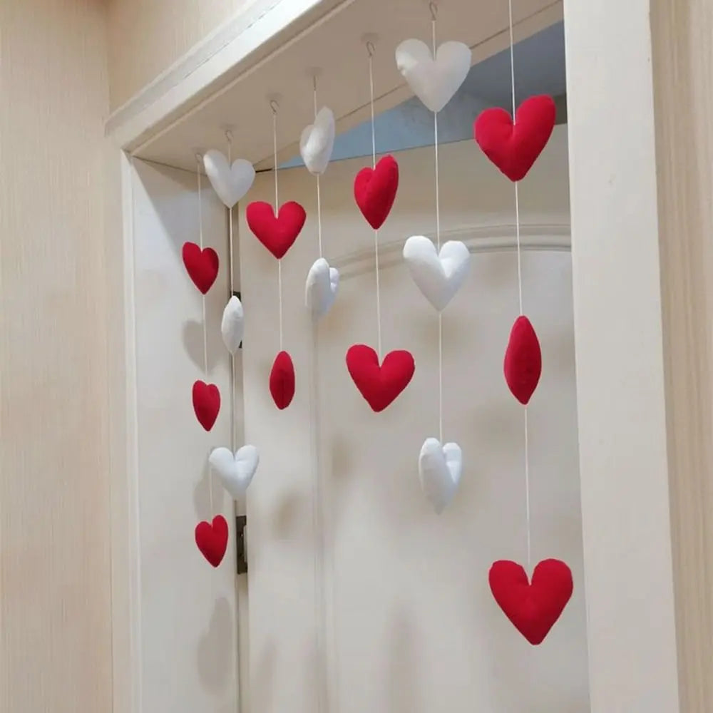 A hanging doorway decoration featuring plush red and white fabric hearts suspended on white strings.