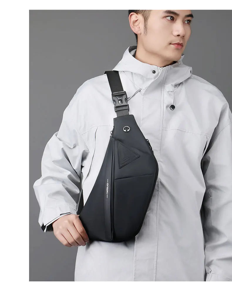A man wearing a sleek, black anti-theft crossbody sling bag with a secure buckle strap and headphone port.
