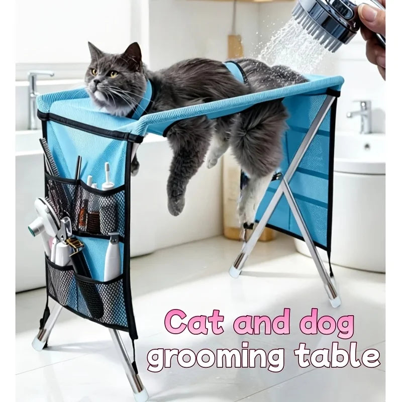 Foldable blue pet grooming table and hammock with metal legs, mesh side pockets, and grooming tools.