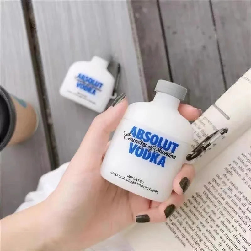 White silicone AirPods case shaped like an Absolut Vodka bottle with a grey cap and black carabiner attachment.