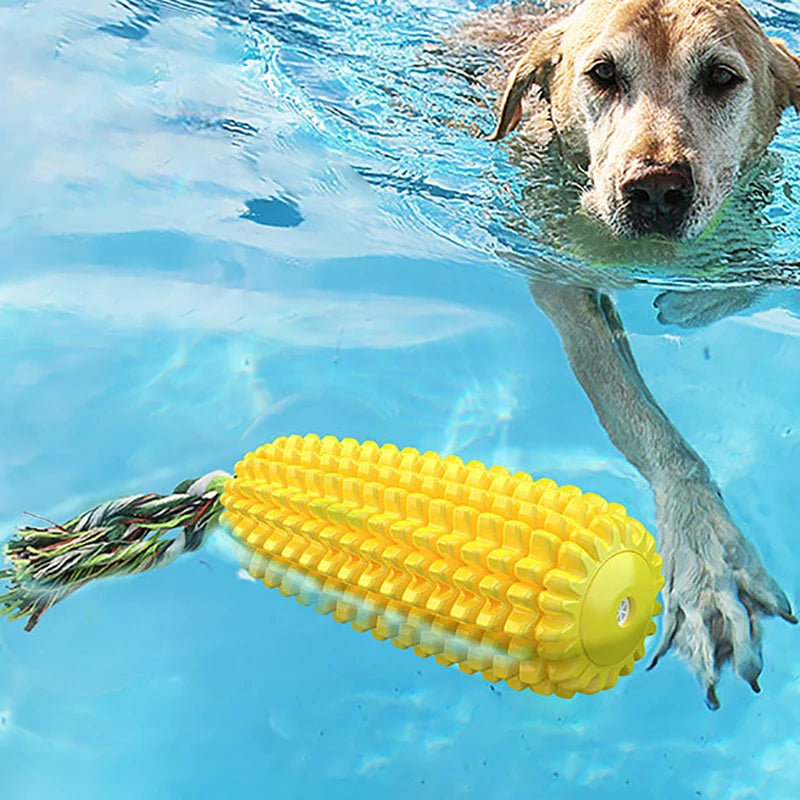 Yellow corn-shaped TPR chew toy with a textured surface, squeaker, and cotton rope tail in a pool.
