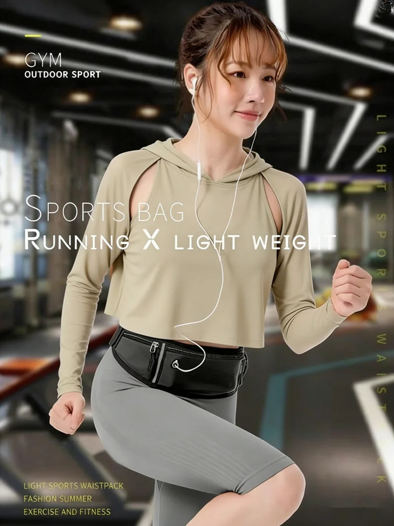A person in a beige hooded gym top wearing a sleek black slimline waist pack for running.